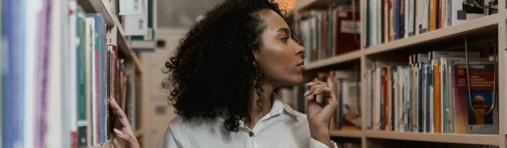 Woman looking for George Orwell book in library to help with copywriting